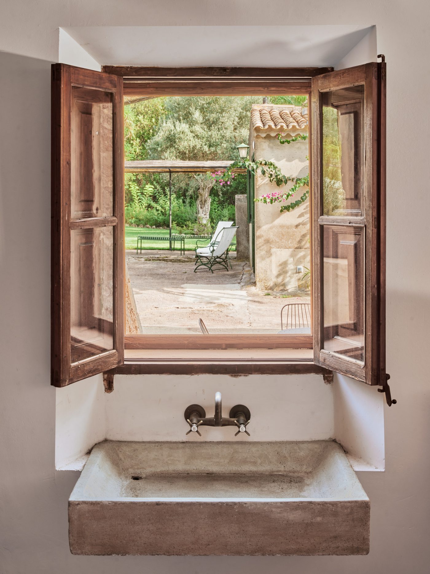 Stone basin beneath a wooden window open to the garden