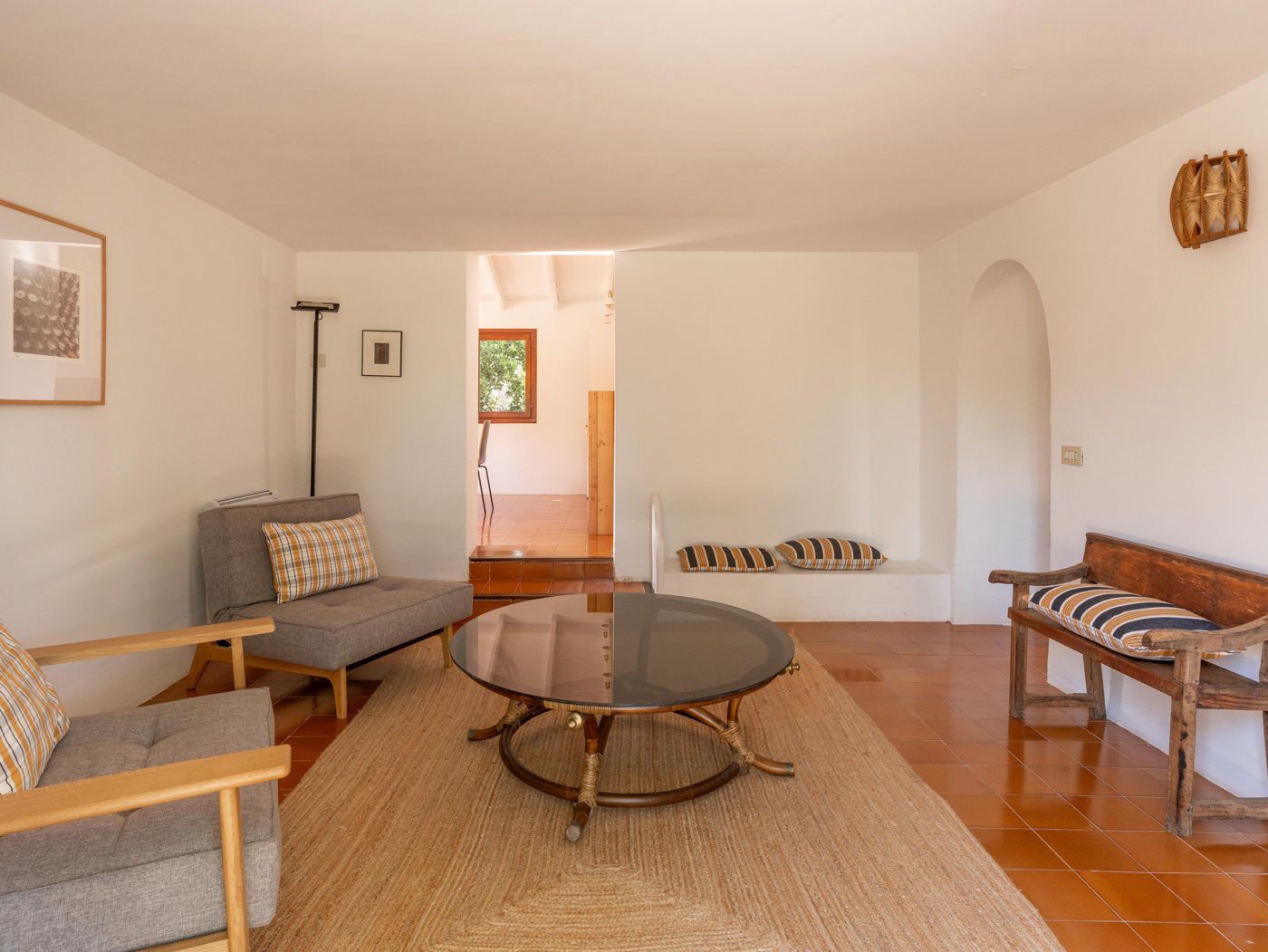 Upstairs living room, with a sofa, armchairs, a glass table and a wooden bench