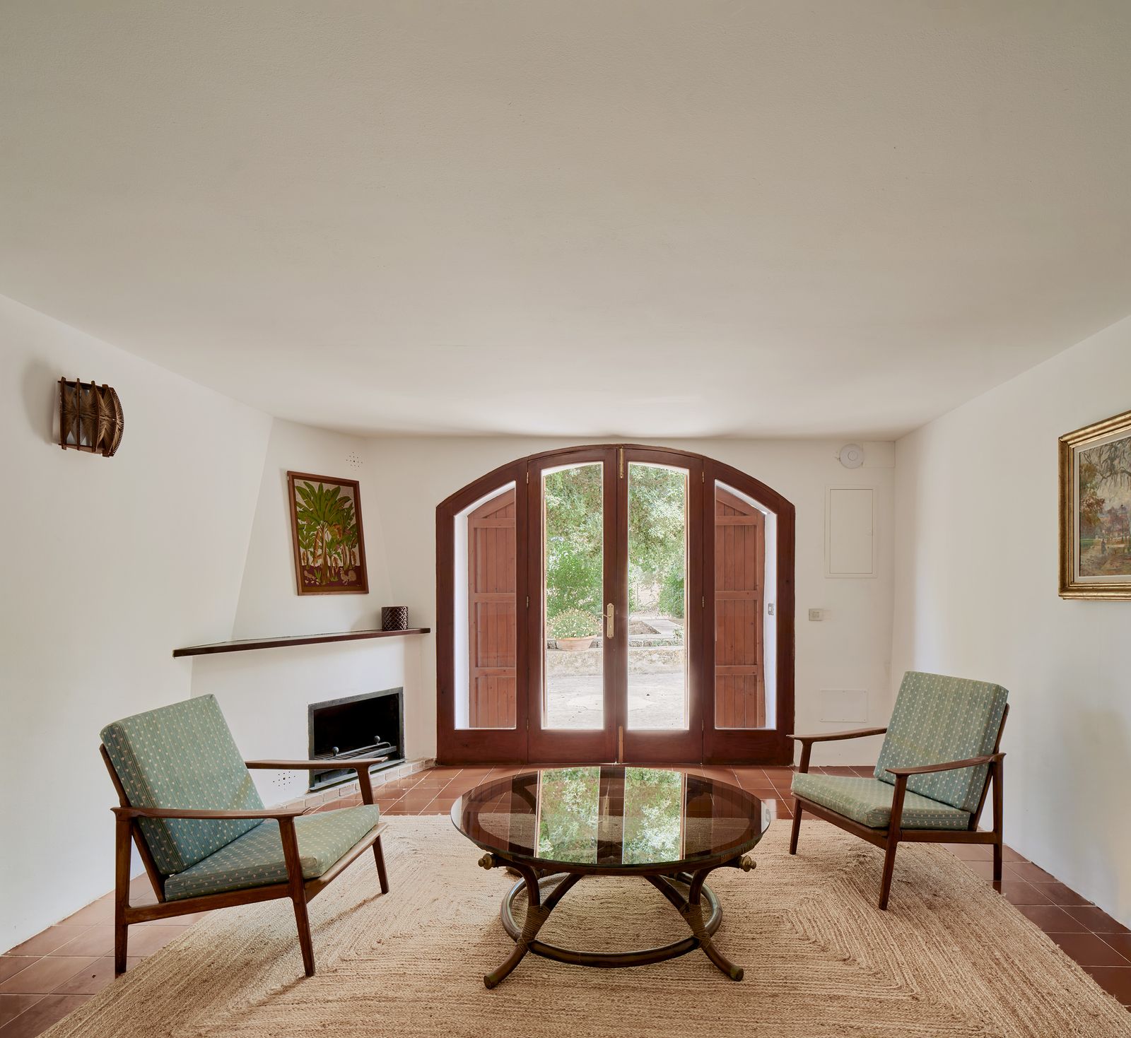 The fireplace living room, with armchairs and an arched door to the garden