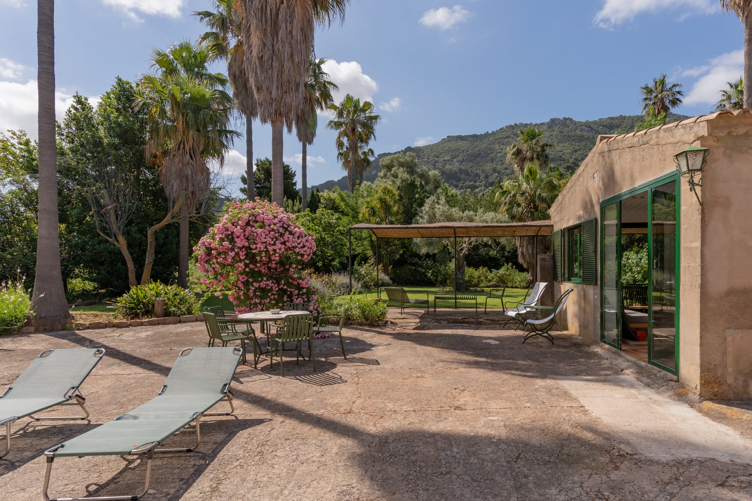 Garden patio with sun loungers and tables in the shade, beside the studio
